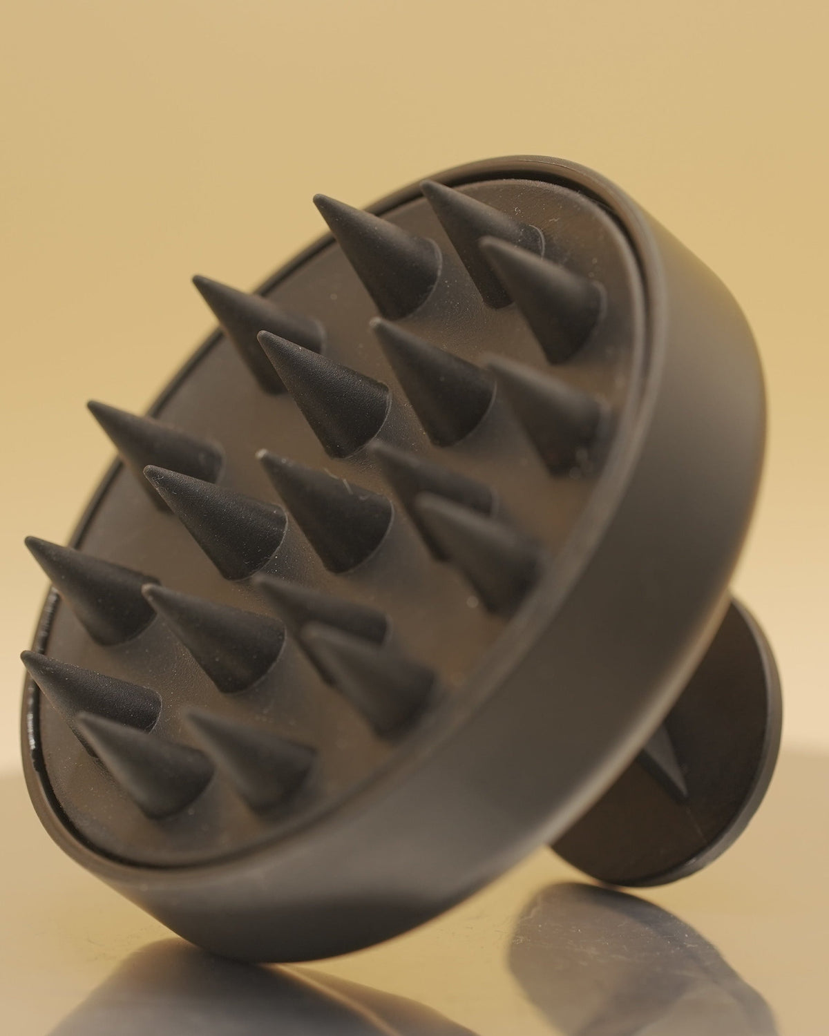 Black scalp massager on a beige background