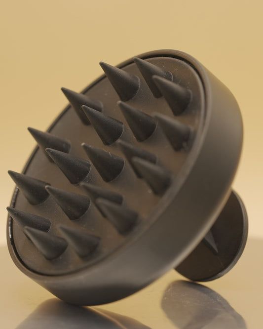 Black scalp massager on a beige background