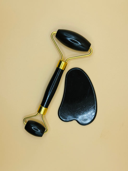 Black facial roller and gua sha tool on a beige background